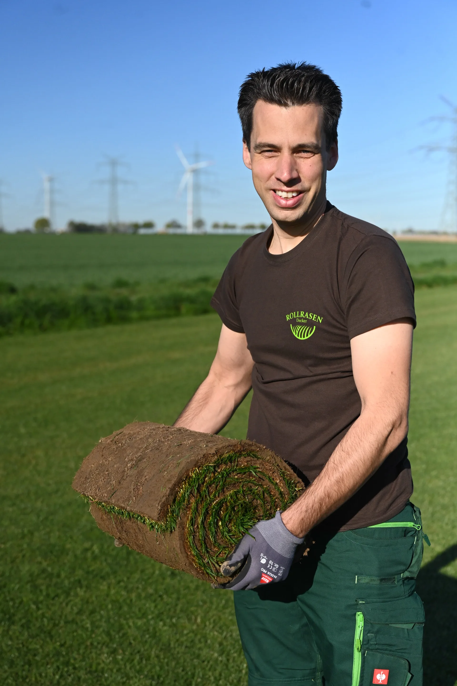 Thomas Decker mit einer frisch geschälten Rolle Rollrasen auf dem Feld